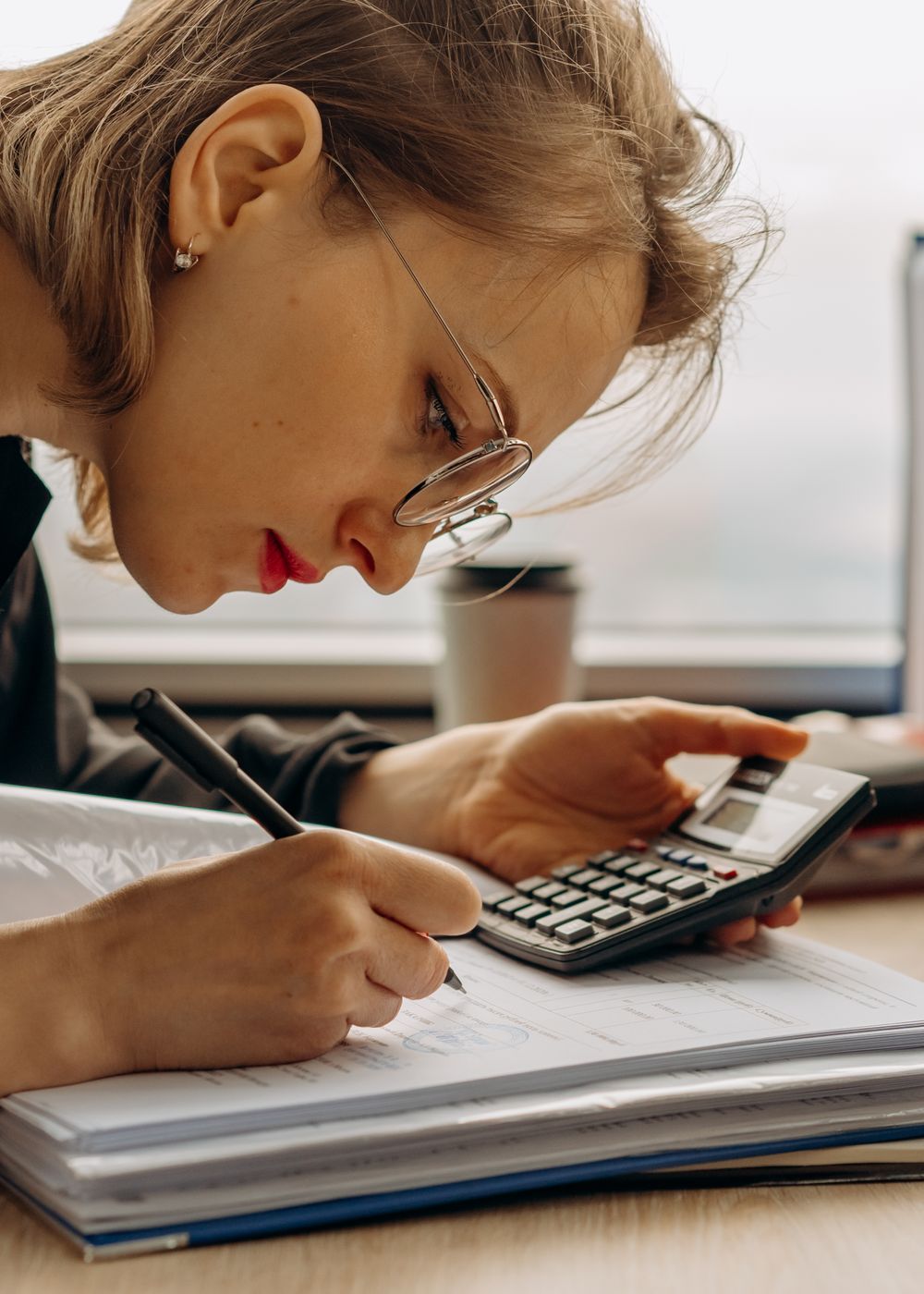 Accountant preparing sales tax filings with a calculator and ledgers