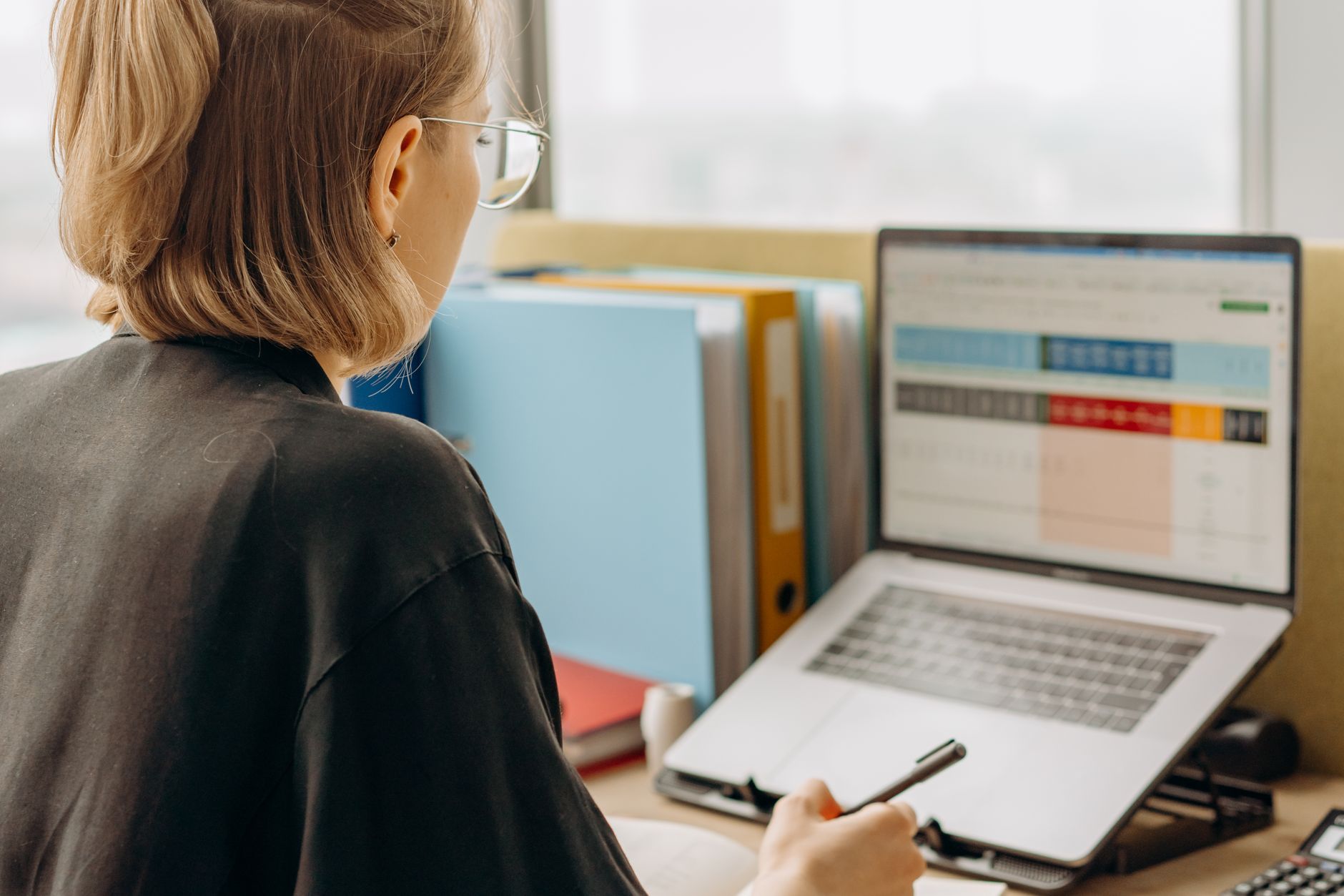 Professional woman reviewing data on laptop, working in modern office environment.
