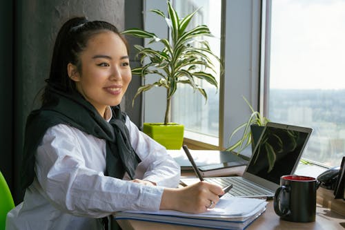 Free A Woman Holding a Pen Looking Afar By the Window  Stock Photo