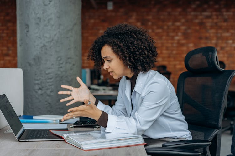 A Frustrated Woman Sitting On A Swivel Chair While Looking At The Screen Of A Laptop