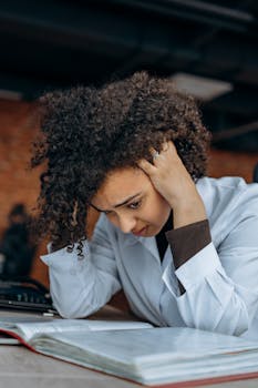 An anxious woman with curly hair showing frustration while working at an office desk.