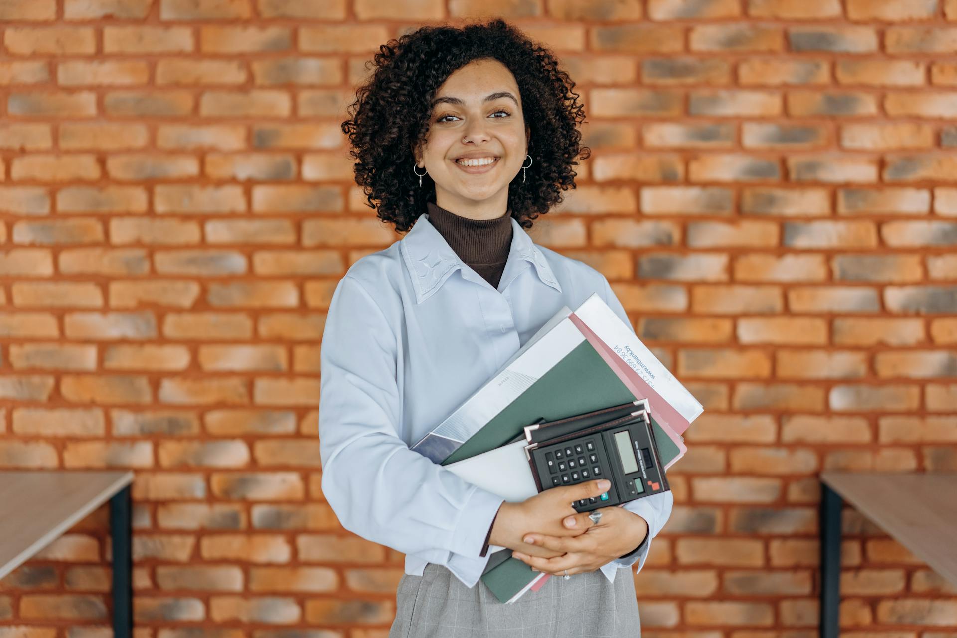 A Working Woman Grasping Folders and a Calculator