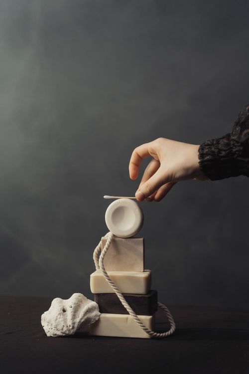 Free Elegant still life of stacked soaps with a human hand, featuring a seashell and rope, captured in soft lighting. Stock Photo