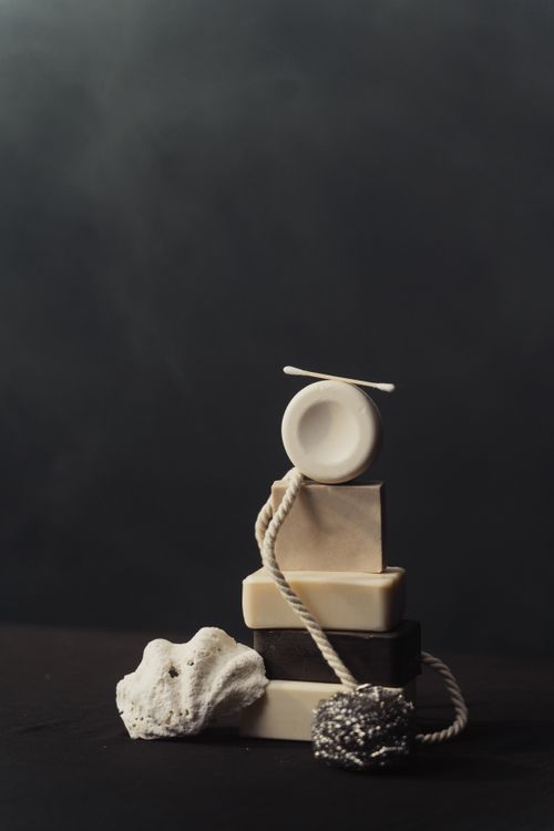 Free Artistic still life of bath essentials including soap and sponge on a dark background. Perfect for lifestyle and hygiene themes. Stock Photo