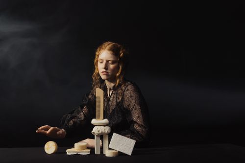 Free Artistic shot of a woman with hygiene products on a black background. Stock Photo