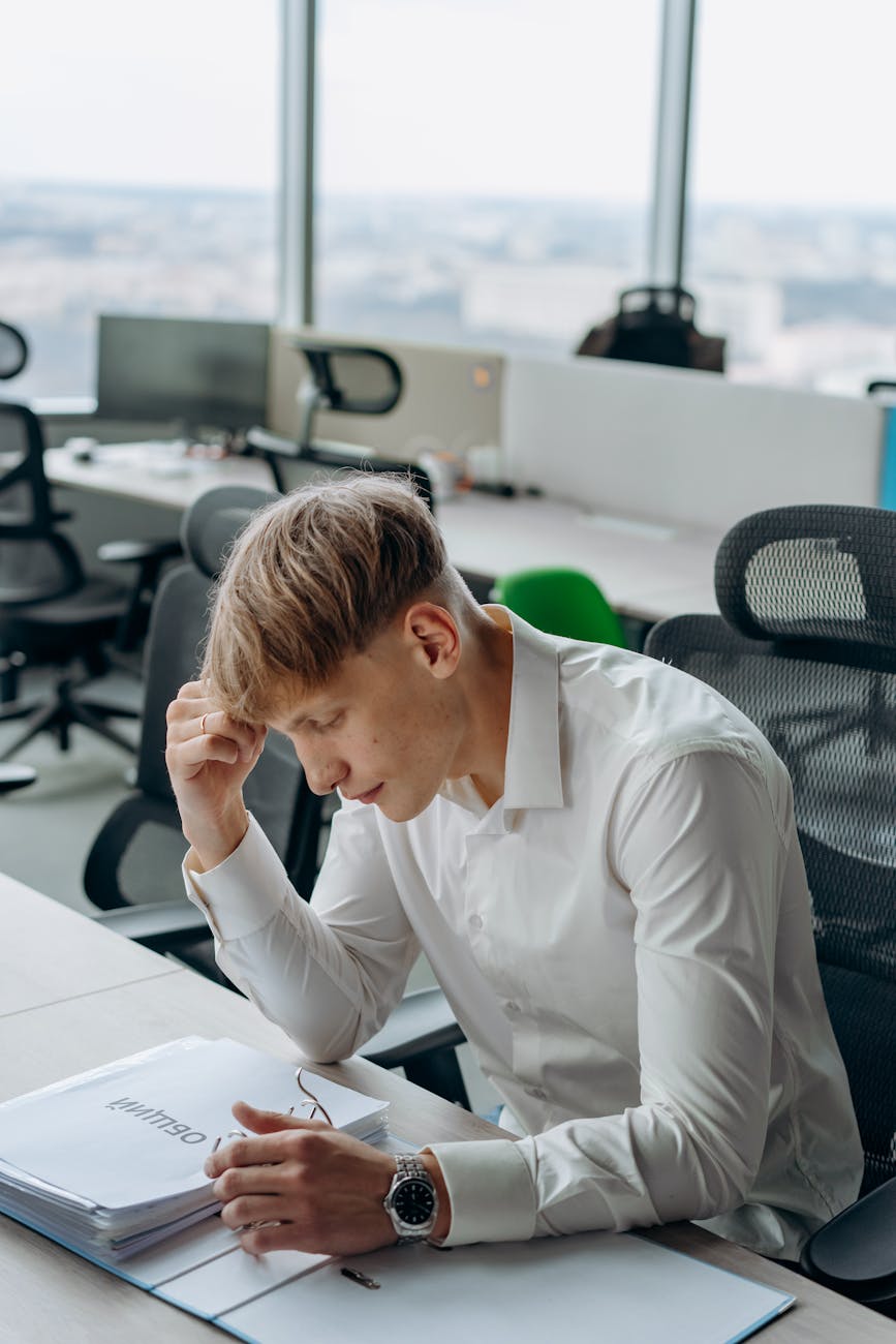 Young Man Feeling Exhausted in White Long Sleeve Shirt Sitting Inside an Office