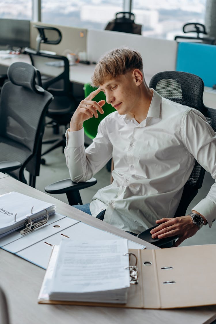 A Man Sitting In The Office While Thinking 