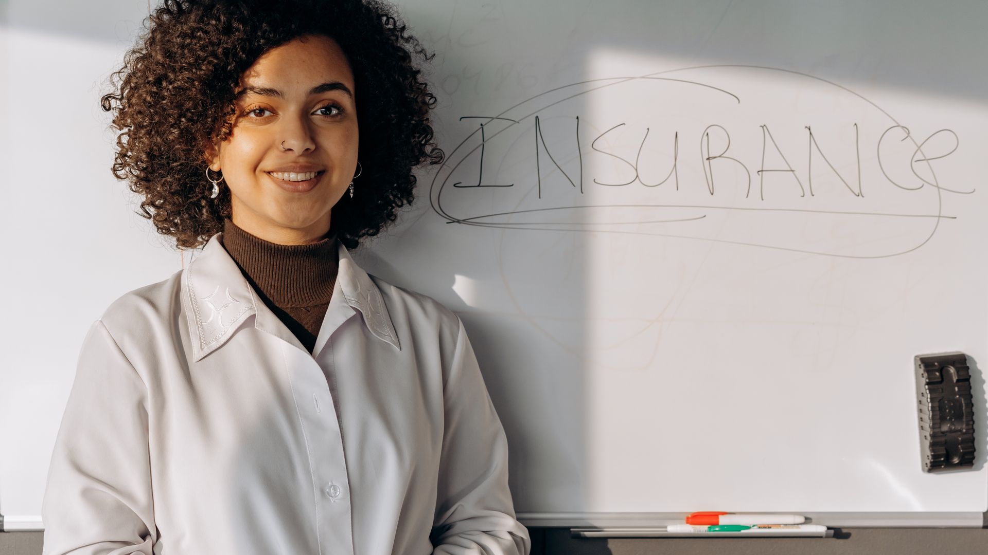 Modafinil Insurance Coverage Guide: Unlocking Your Benefits African American woman smiling in office setting with a whiteboard displaying 'Insurance' — modafinil insurance coverage guide