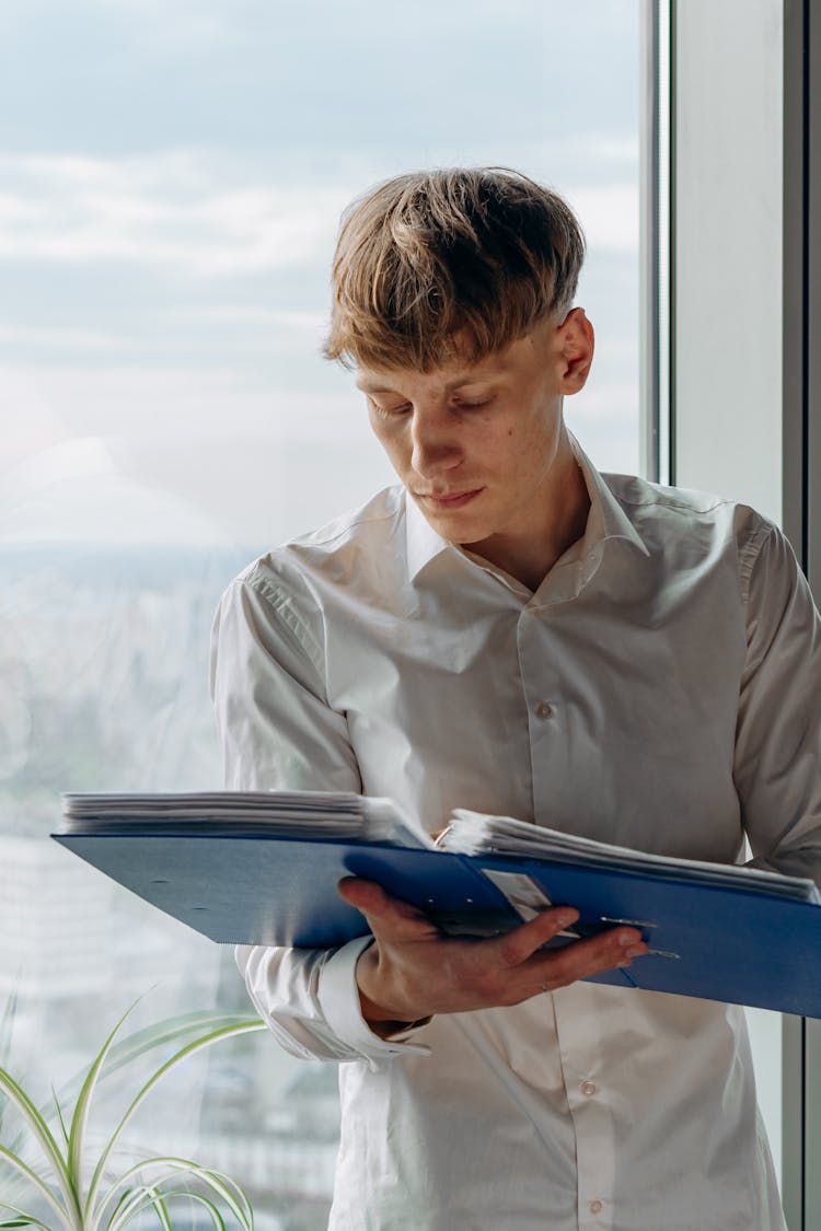 A Man Reading Documents In A Binder