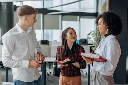 A group of cheerful coworkers discussing a project in a bright, modern office setting.