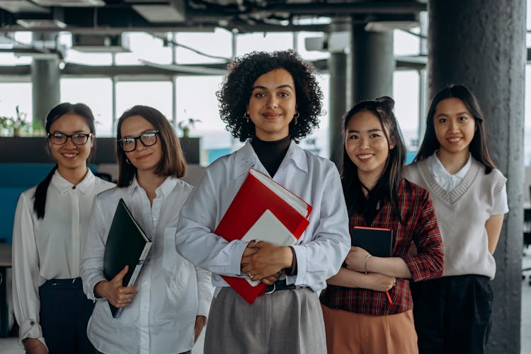 A Group Of Women Holding Binders