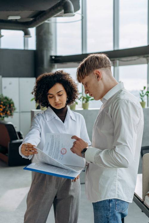Free Two professionals discussing paperwork in a modern office setting. Stock Photo