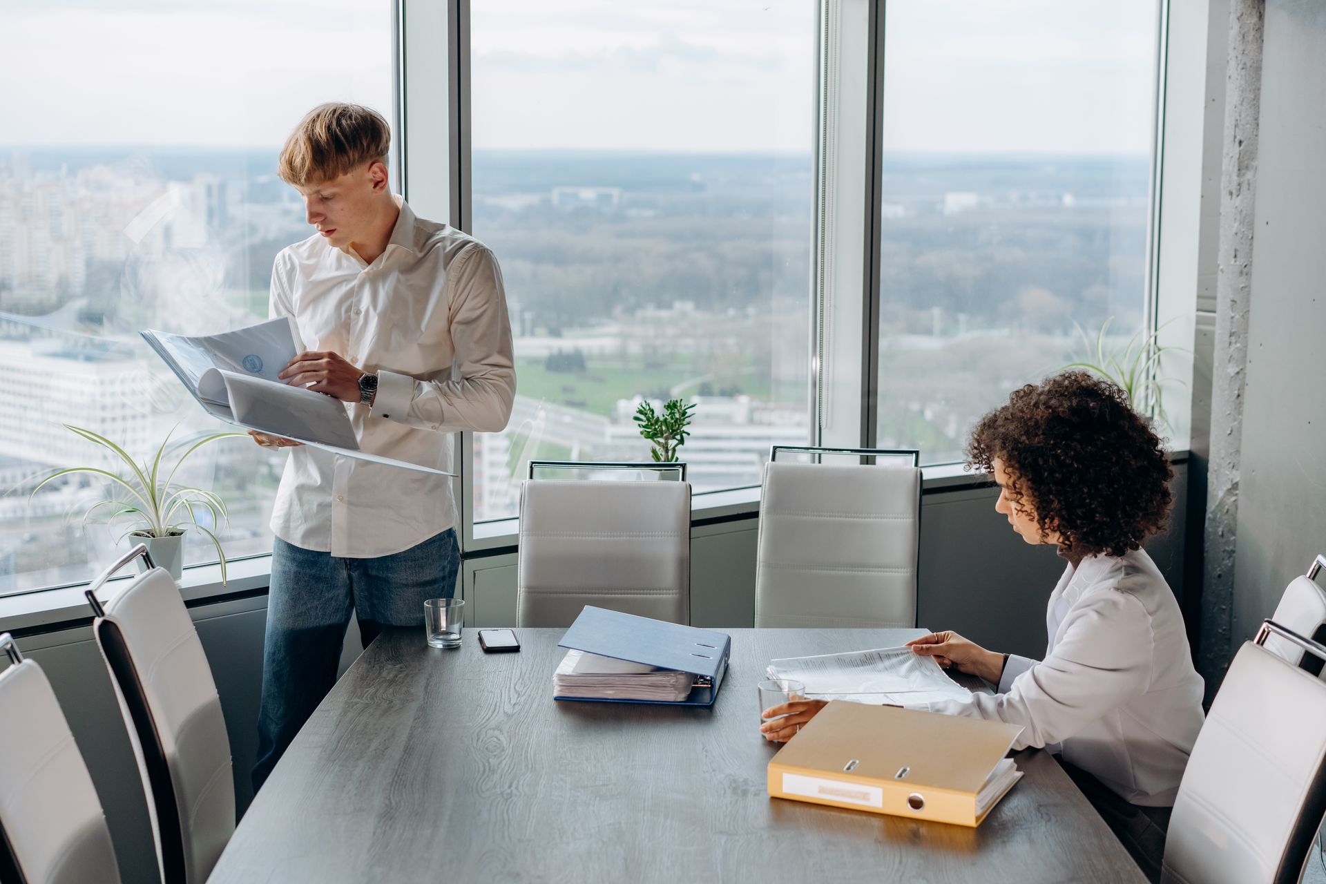 Business professionals reviewing documents in a modern office with city view, teamwork and collaboration concept.