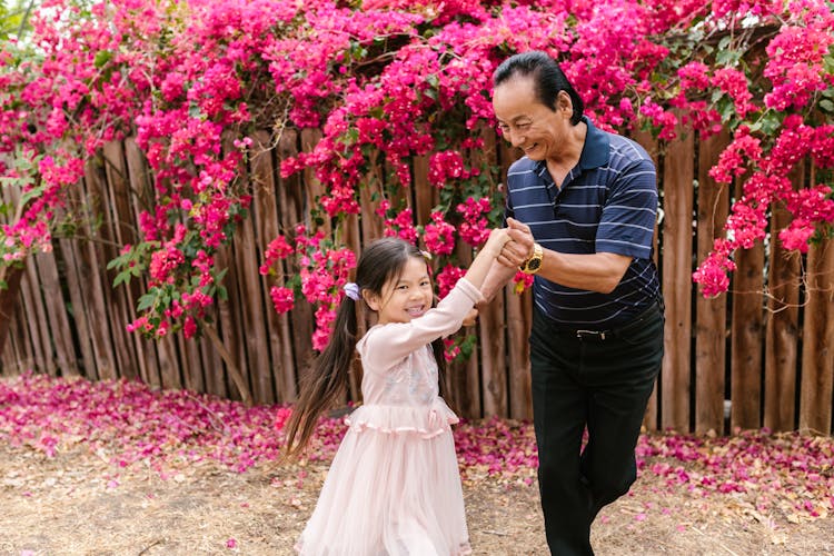 A Man In Striped Shirt Dancing With A Girl In A Pink Dress