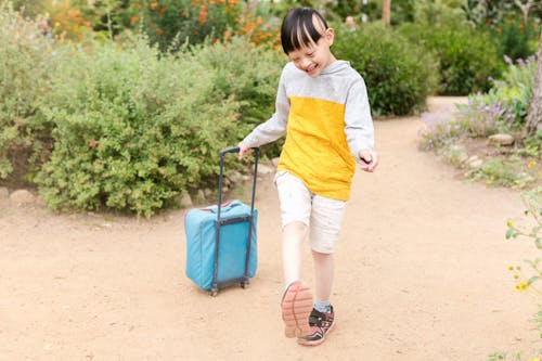 A Boy Walking while Pulling the Stroller