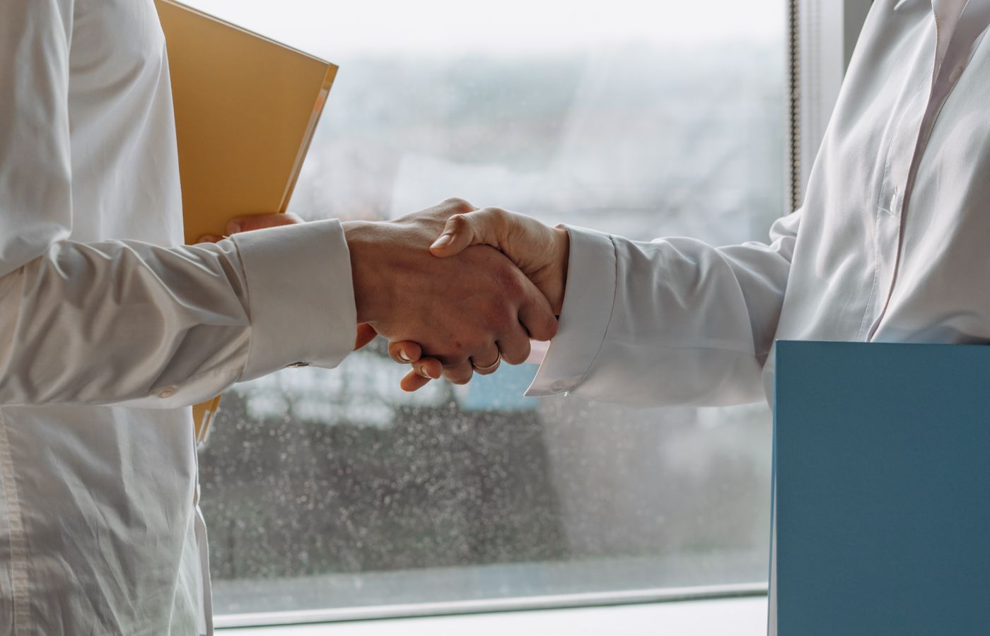 Two business professionals shaking hands indoors, symbolizing agreement.