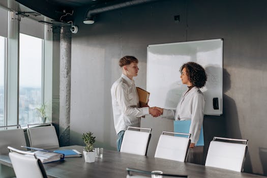 Business colleagues shaking hands in a conference room after a meeting.