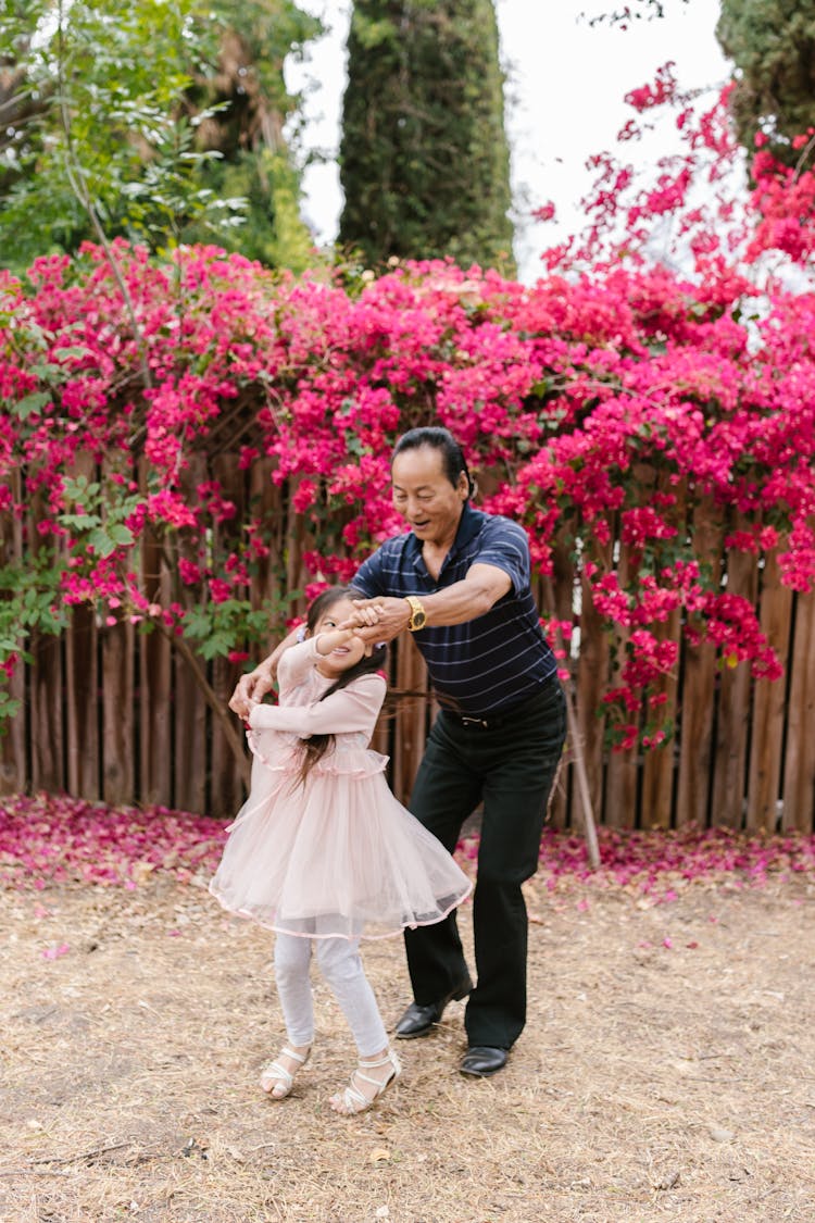 A Man And Girl Dancing Near The Red Flowers