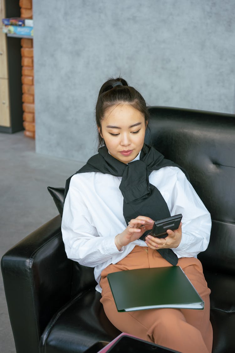 A Woman Relaxing On A Couch While Using A Calculator