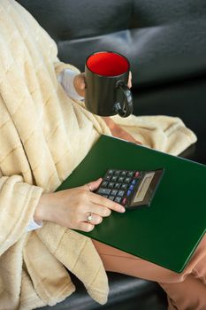 Person holding a mug while using a calculator, wrapped in a towel.