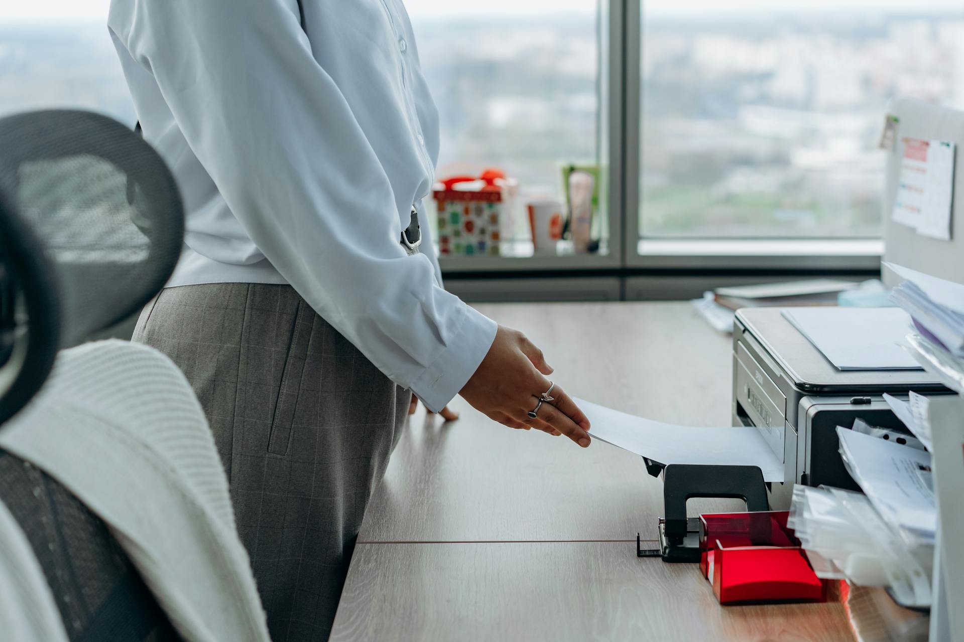 Business professional printing a document in an office environment.