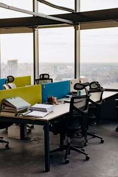 Open office space with colorful dividers and a city view, typifying modern urban work environments.