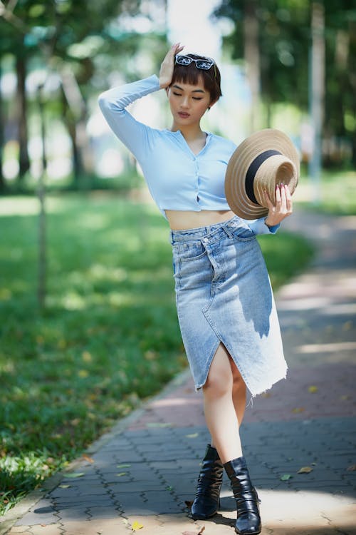 Woman in Blue Crop Top and Denim Skirt Holding a Hat