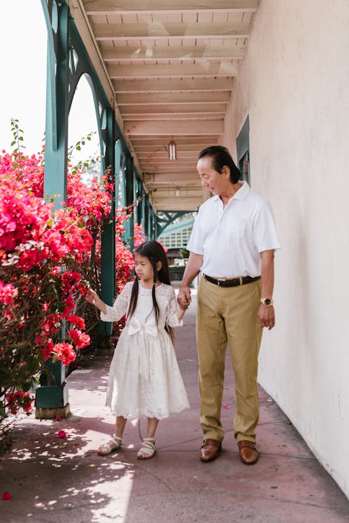 A Man Holding Hands of a Young Girl while Looking at the Flowers