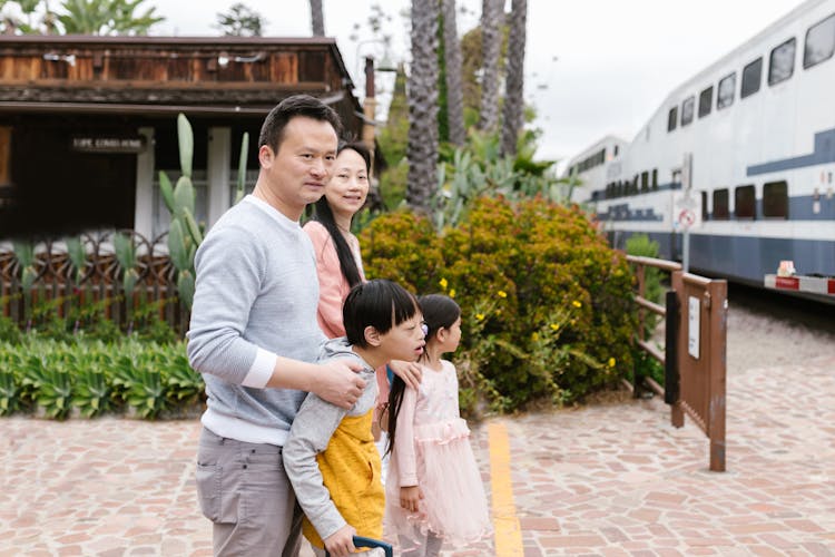 Parents With A Down Syndrome Son And Cute Daughter Standing On Train Station Platform