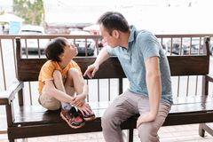 A heartfelt interaction between father and son sitting on a wooden bench outdoors, promoting bonds and autism awareness.