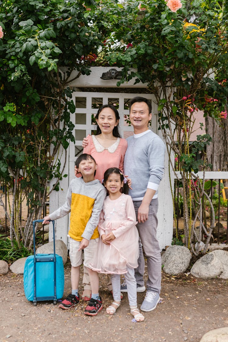 Parents With A Down Syndrome Son And Cute Daughter Standing On A Park