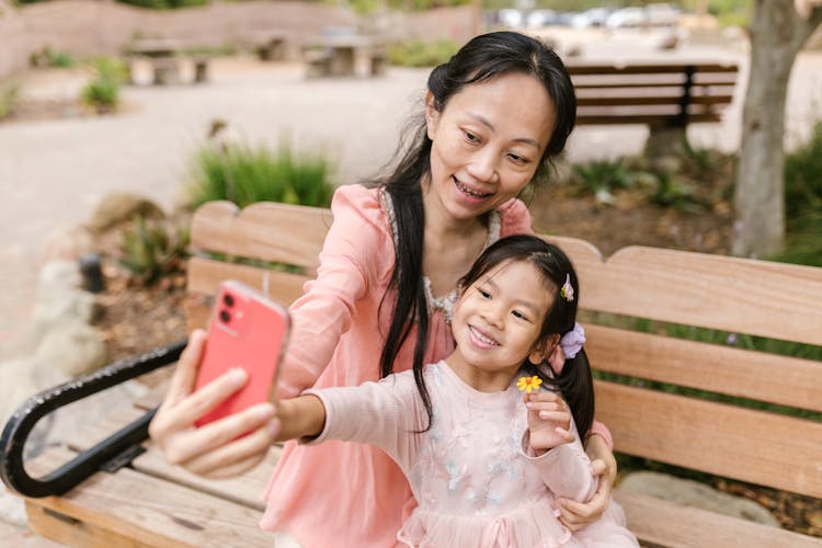 A Child Taking A Photo With Her Mother