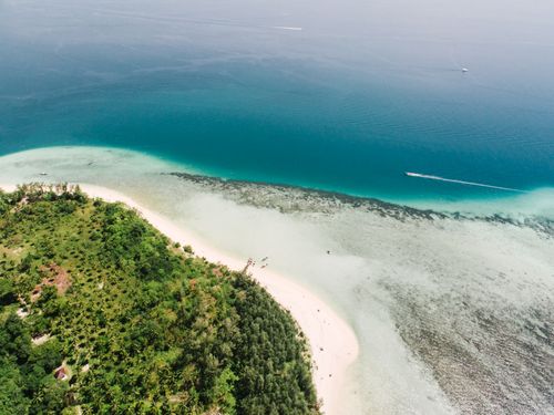 Free A breathtaking aerial view of a lush tropical island meeting the clear blue ocean. Stock Photo