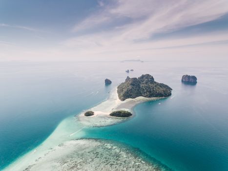 Stunning aerial view of a tropical island surrounded by blue ocean waters under a clear sky.