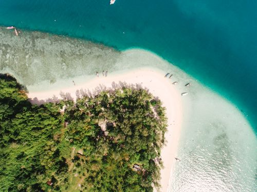 Free Stunning aerial shot of a lush green island with white sandy beach and turquoise waters. Stock Photo