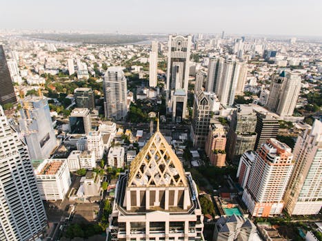 High-angle view of the bustling Bangkok cityscape under clear summer skies, showcasing modern architecture.