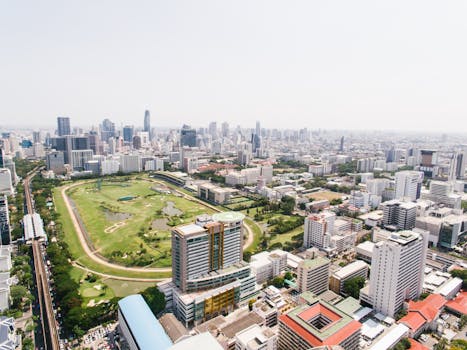 Stunning drone view of Bangkok's cityscape featuring skyscrapers and a lush racecourse.