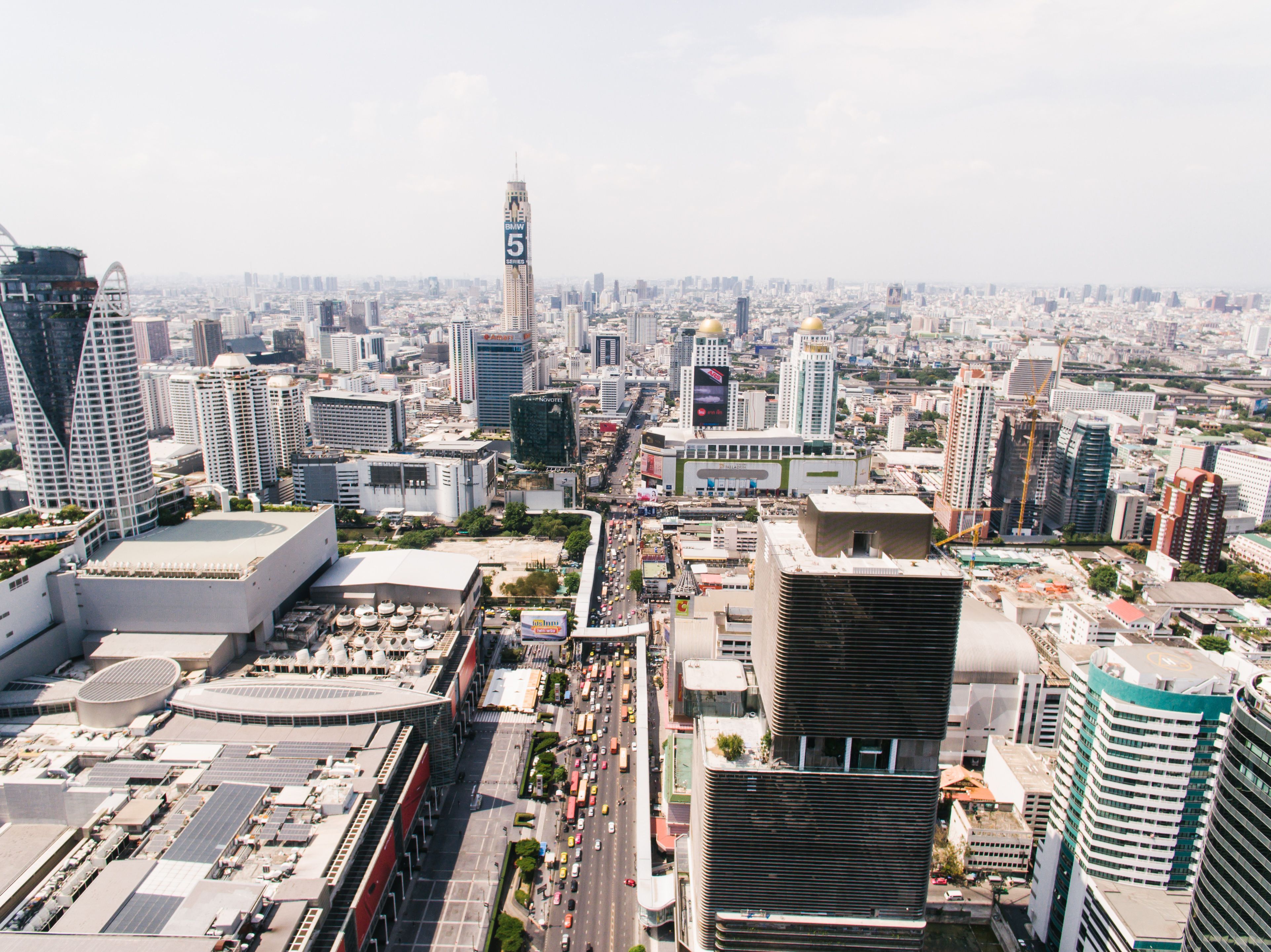 Stunning aerial view of Bangkok's bustling cityscape and skyscrapers on a sunny day.