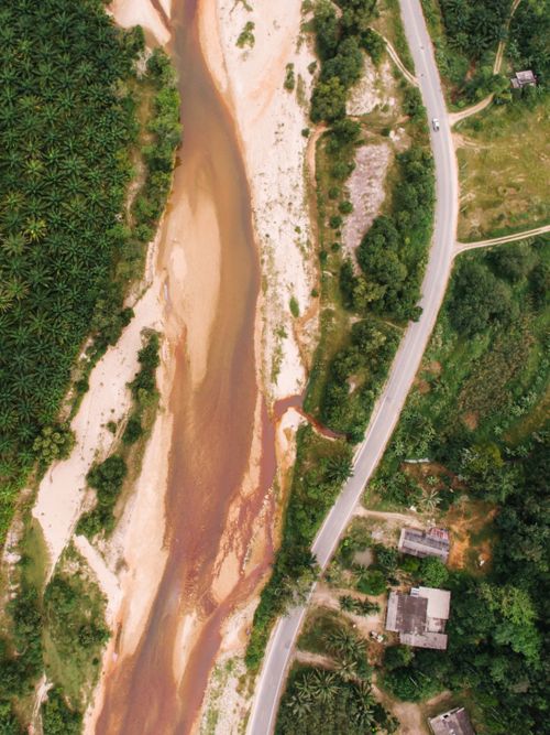 Free Drone photo of a winding river in a rural setting with greenery. Stock Photo