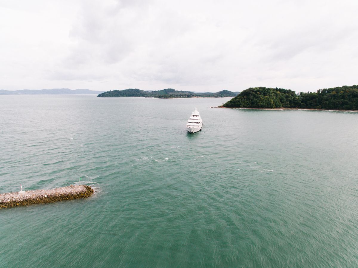 White superyacht cruising between green islands