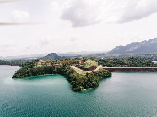 Free Breathtaking aerial view of a lush island with surrounding blue waters and distant mountains. Stock Photo