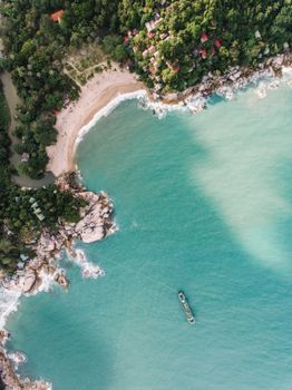 Stunning aerial view of a tropical beach with lush greenery and turquoise waters.