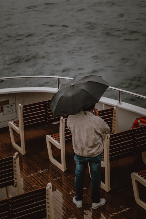 Man with an Umbrella Standing on the Boat and Looking at Sea 