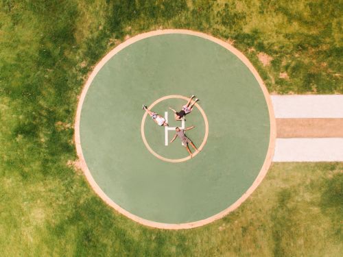 Free A top-down view of four people lying on a helipad surrounded by grass. Stock Photo