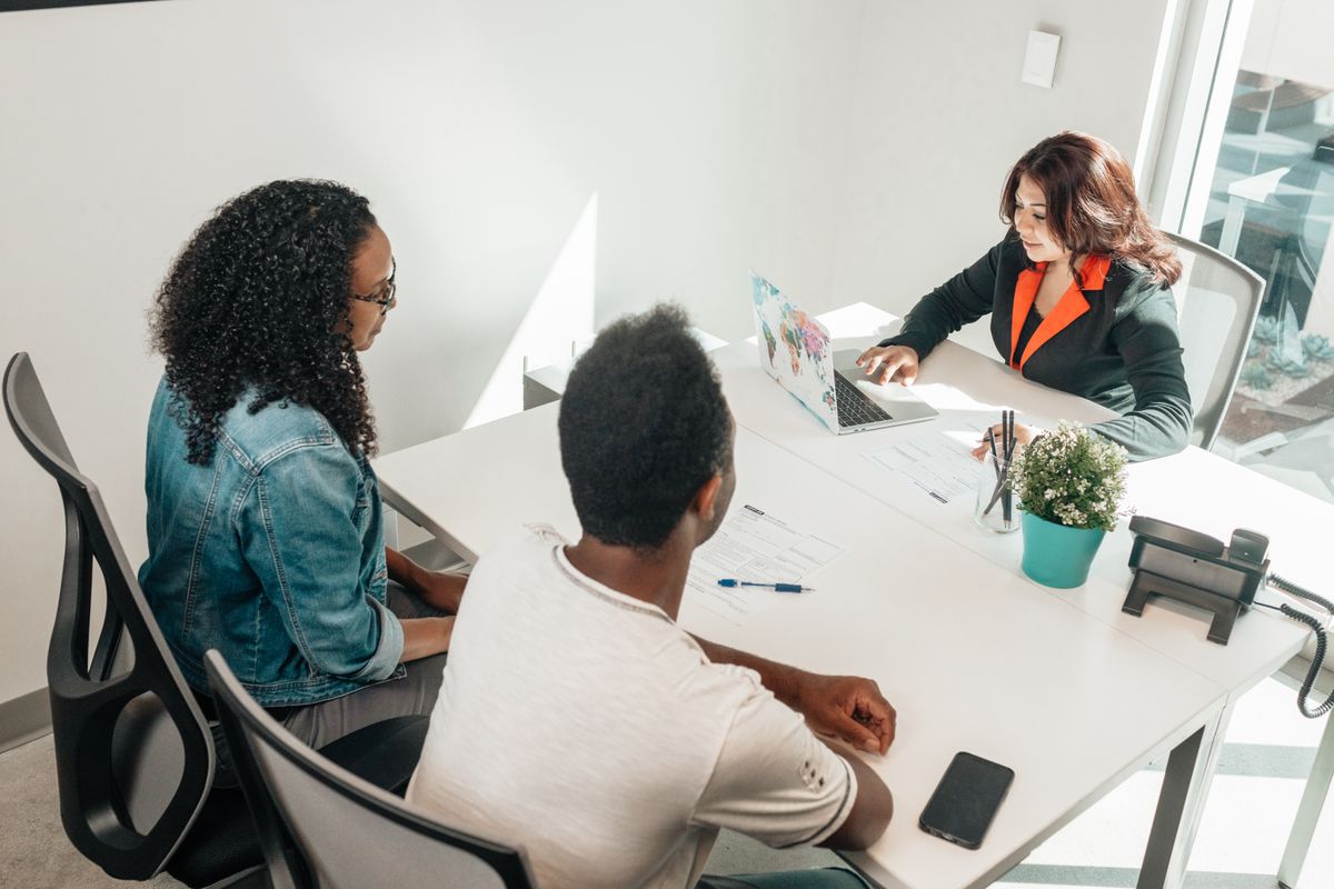 Business professionals discussing work around a laptop and documents in a bright office
