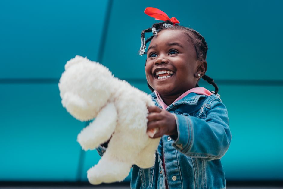 A child smiling while holding a colorful handmade doll - Craft and donate toys A child smiling while holding a colorful handmade doll - Craft and donate toys