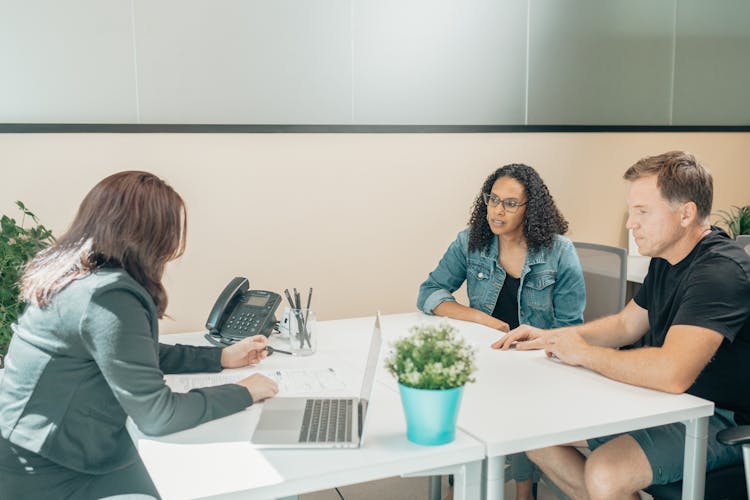 Unrecognizable Worker Talking To Multiethnic Clients At Desk With Laptop