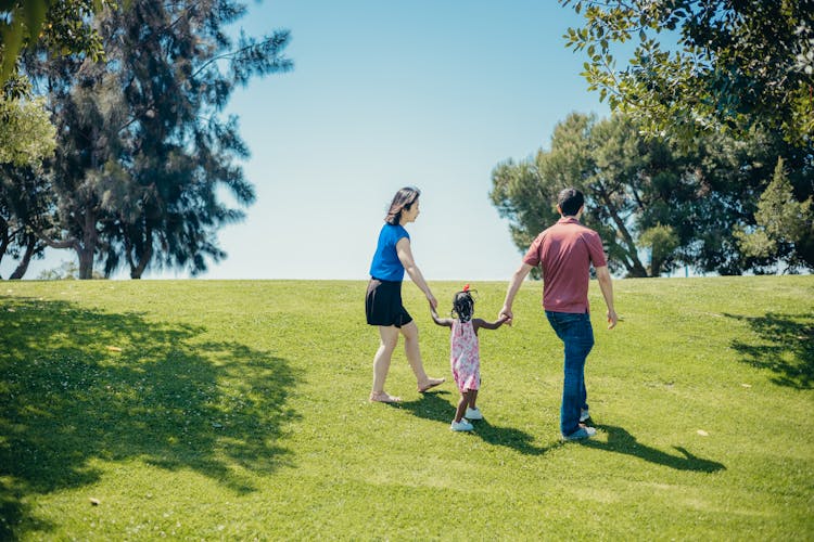 Family Walking On A Grass Field