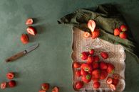 Top-down view of strawberries arranged on a tray with scattered slices and a knife.