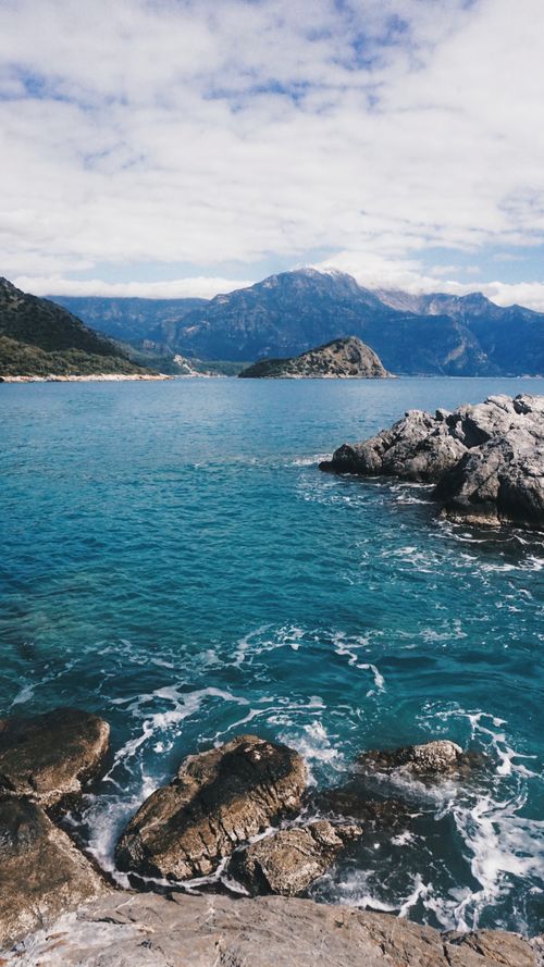 Free Breathtaking coastal scenery with rocky shores and majestic mountains meeting the blue sea. Stock Photo